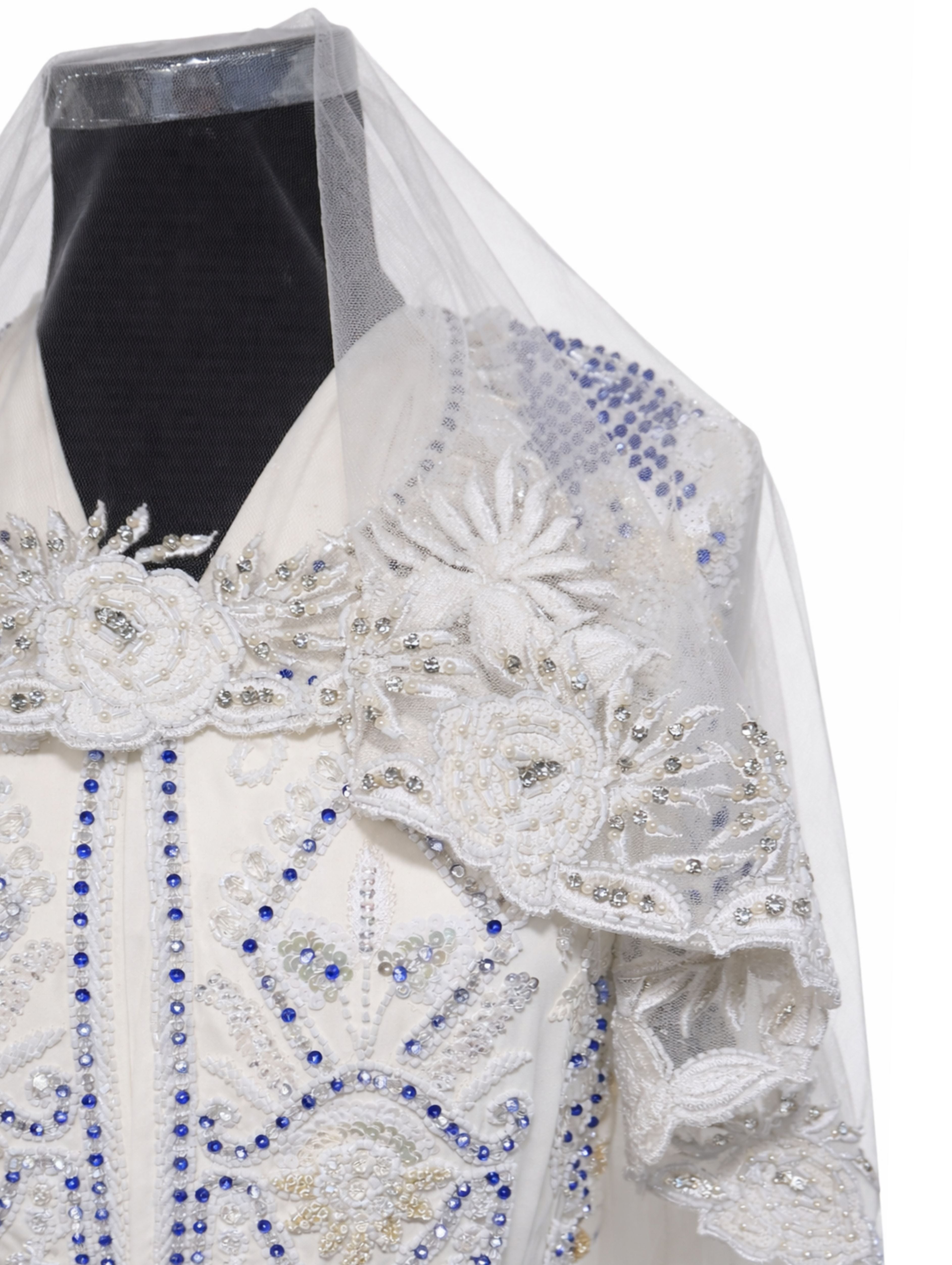 Gebroken witte ronde bruidssluier met bloemen, parels en steentjes gedragen over een bruidsjurk.