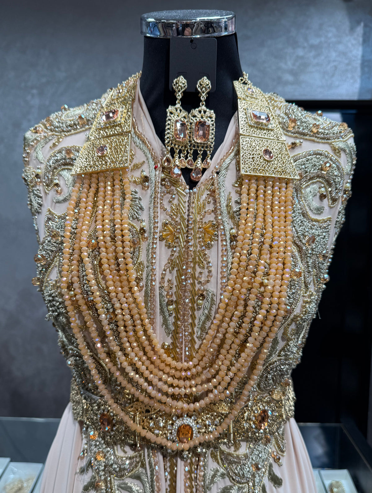 Gouden Marokkaanse kralenketting met zalmkleurige stenen, meerdere lagen kralen en bijpassende oorbellen.