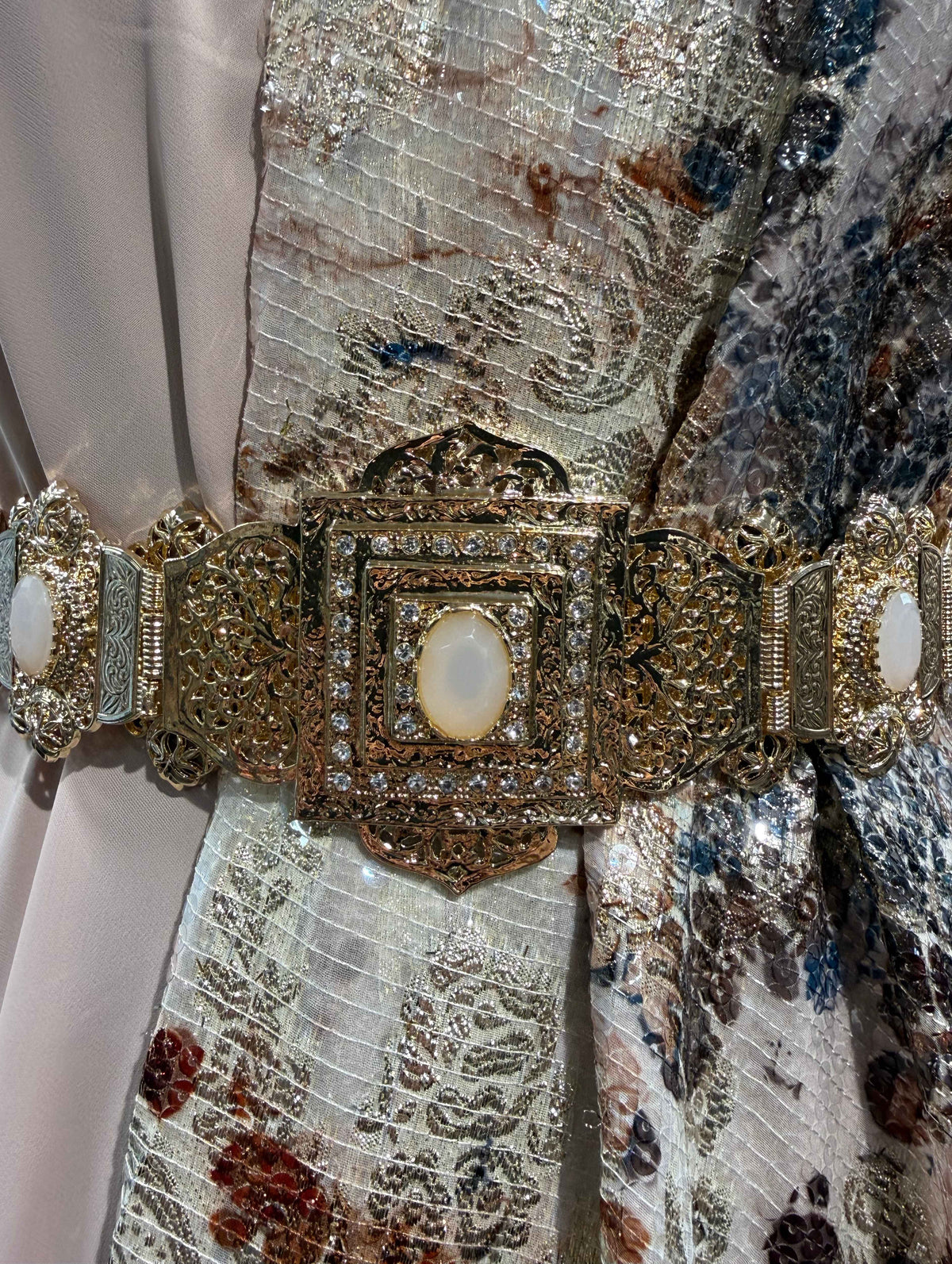 Gouden Marokkaanse Beldi mdamma riem met poederroze stenen, sierlijke metalen schakels en een decoratieve centrale sluiting.