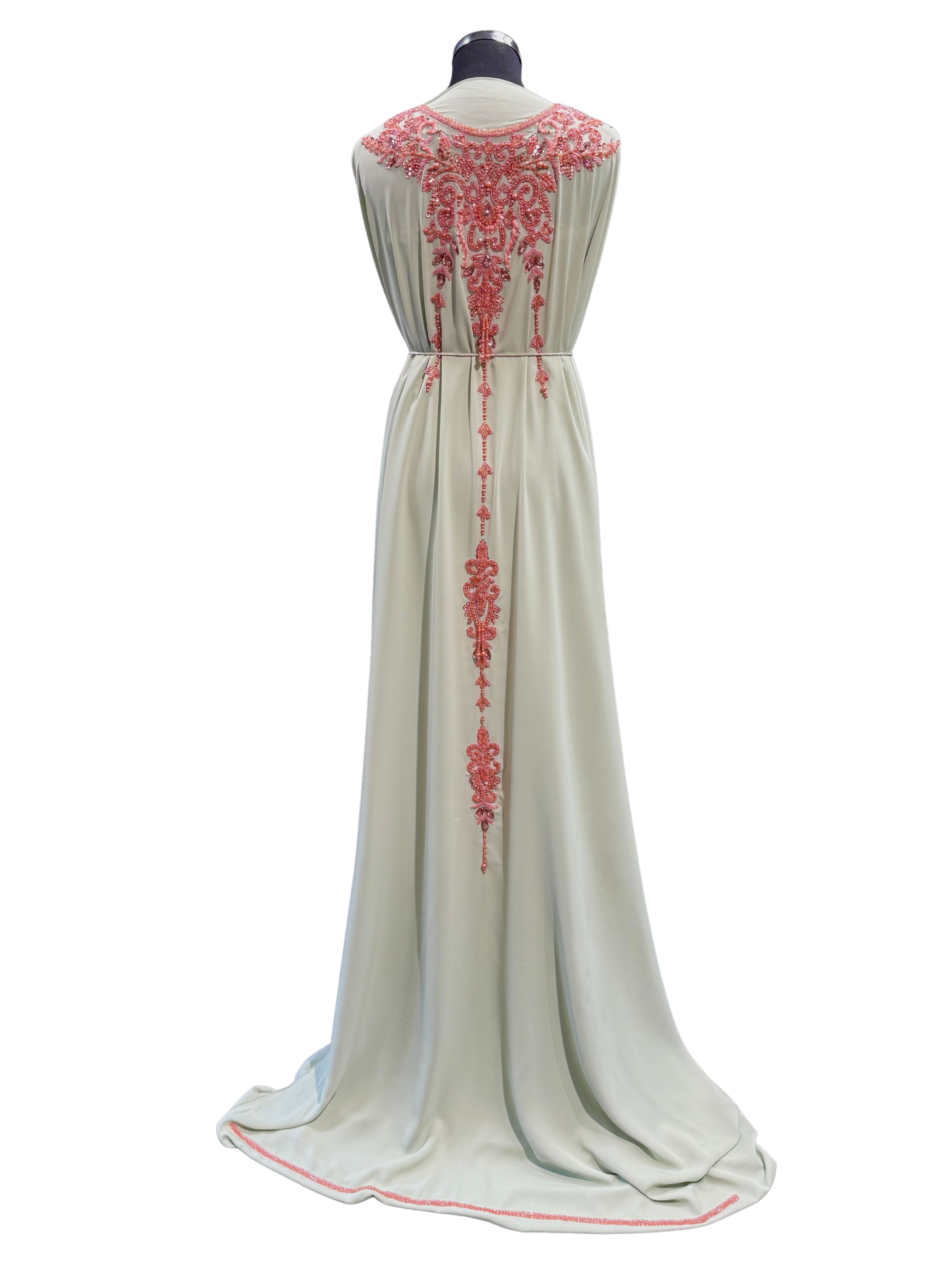 Achterkant van mint groene soepel vallende caftan stof met donkerzalmkleurig borduursel, stenen en kralen.