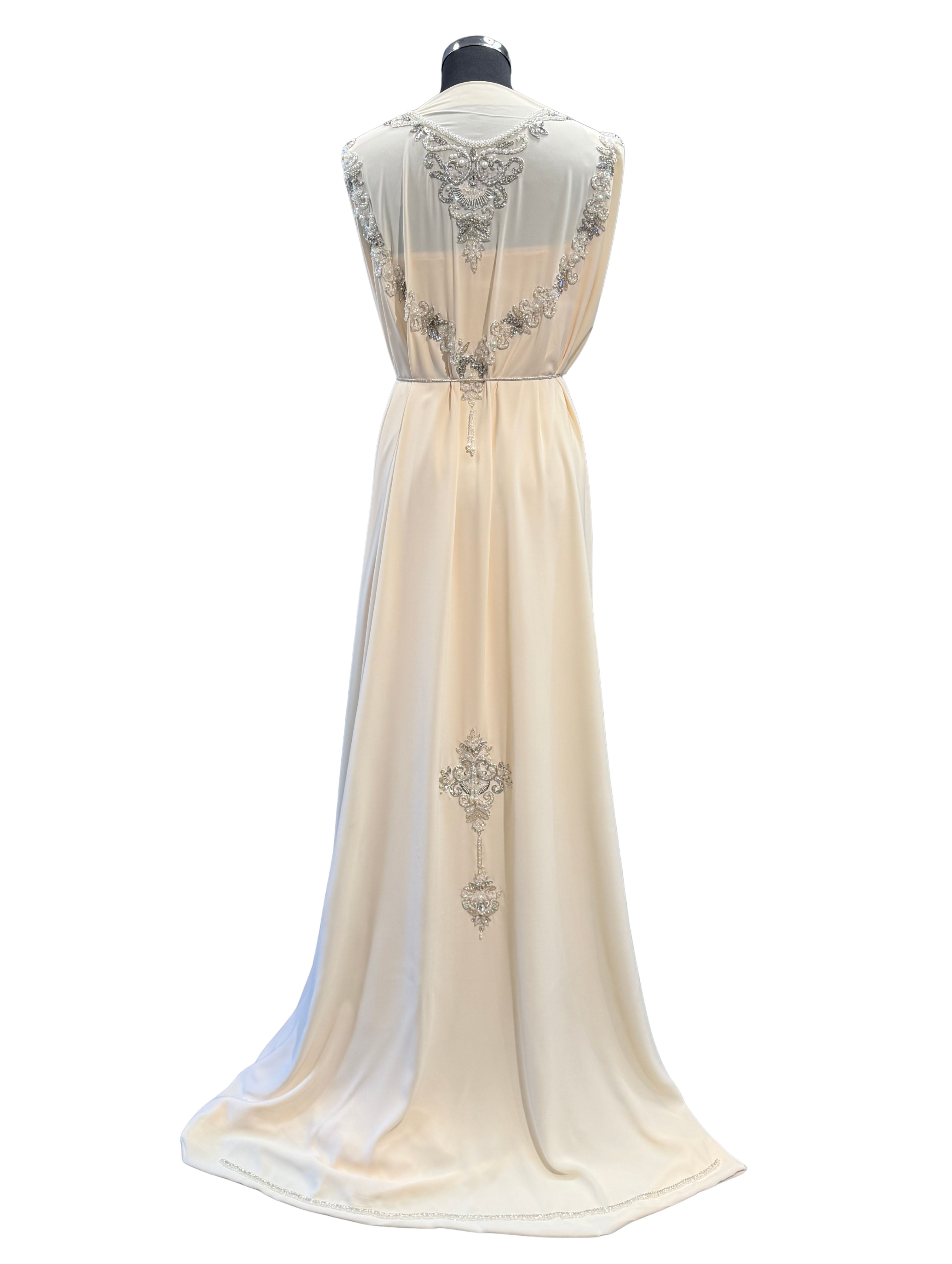 Achterkant van ivoorcrème takshita stof, verfijnd bewerkt met zilverkleurige accenten, kraaltjes en steentjes.