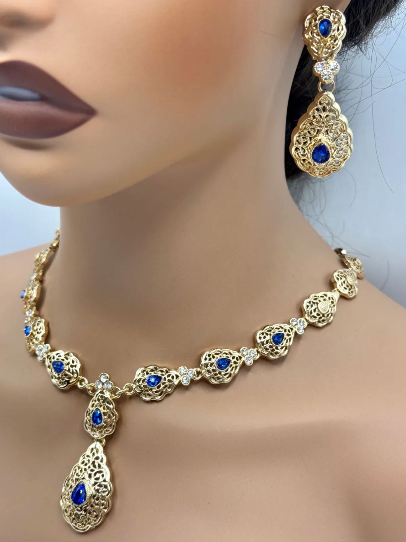 Elegante gouden ketting met bijpassende oorbellen, versierd met fonkelende kobalt blauwe stenen voor een luxe uitstraling