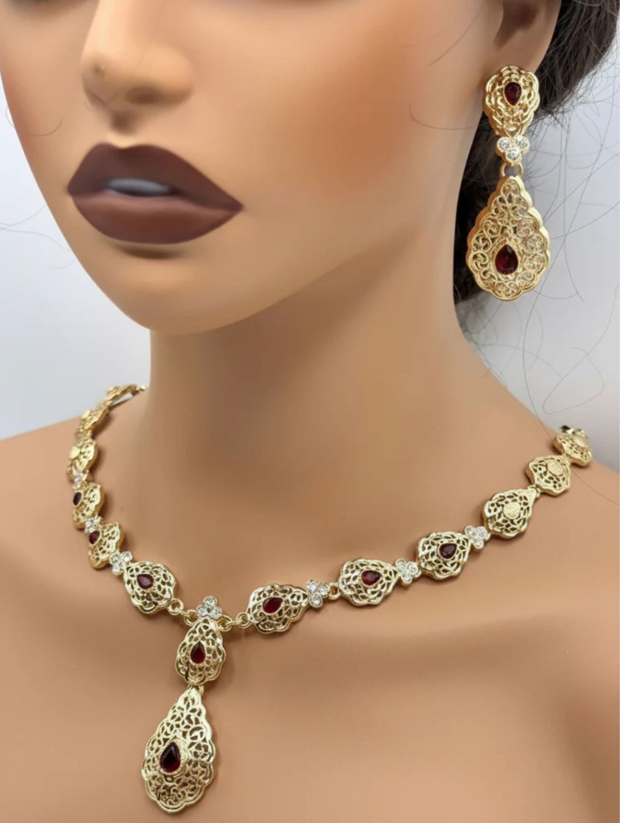 Elegante gouden ketting met bijpassende oorbellen, versierd met fonkelende rode stenen voor een luxe uitstraling