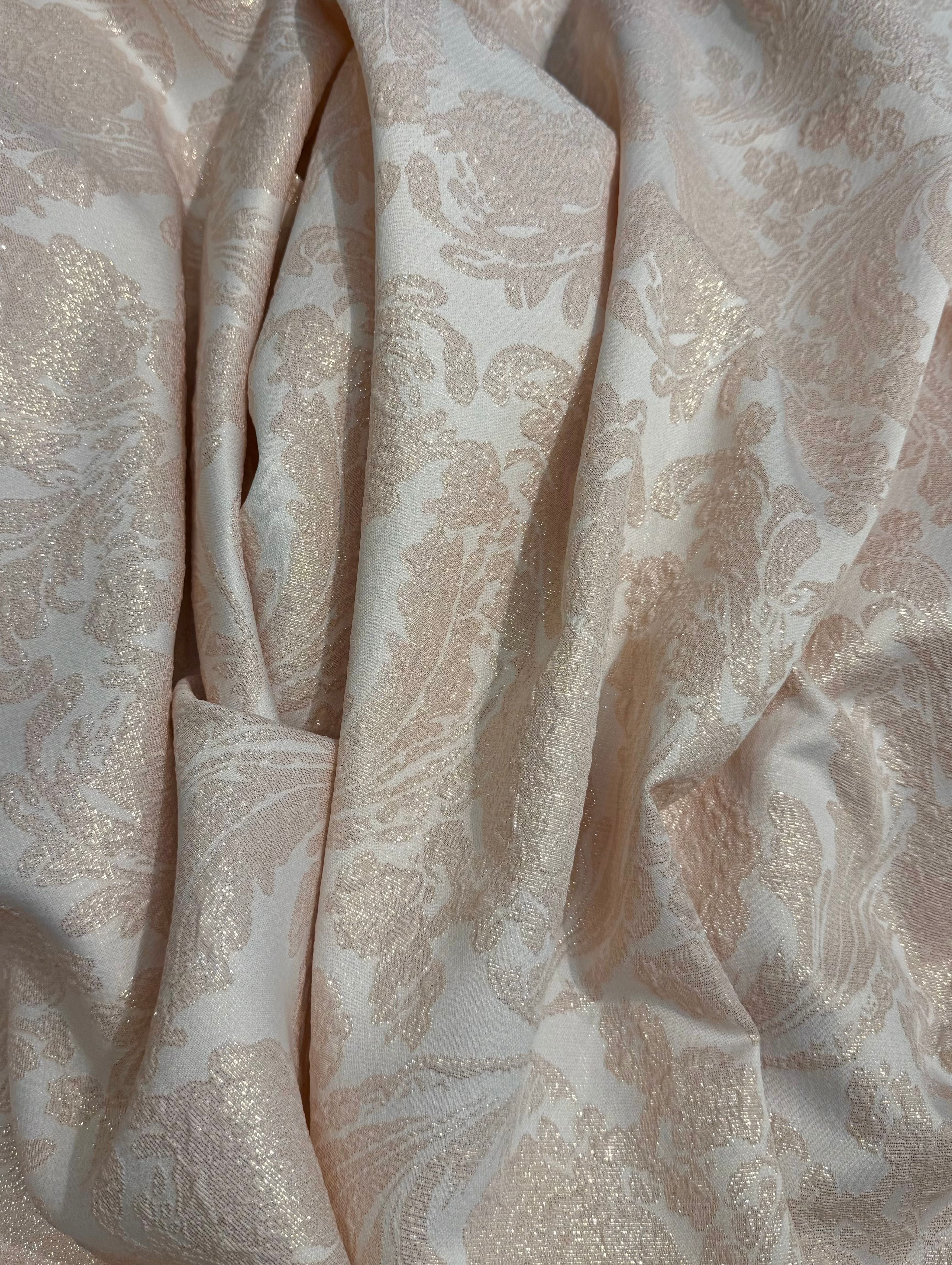 Soepelvallende brokaat stof in poederroze met subtiele glans en verfijnde structuur.