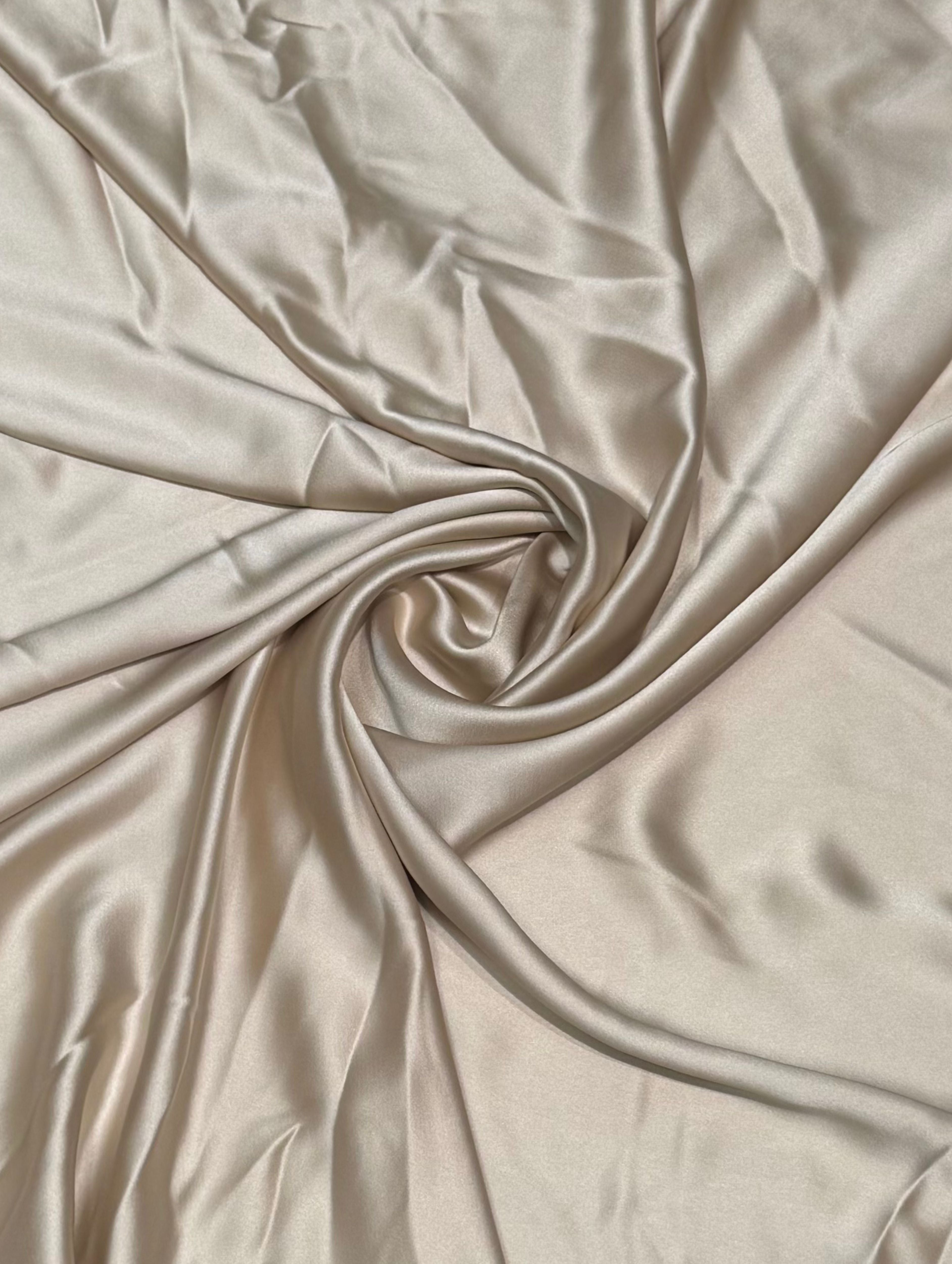 Champagnekleurige crepe satijn stof met luxe zijdeglans en soepelvallende kwaliteit, geschikt voor caftans, takshita's en exclusieve kledingstukken.