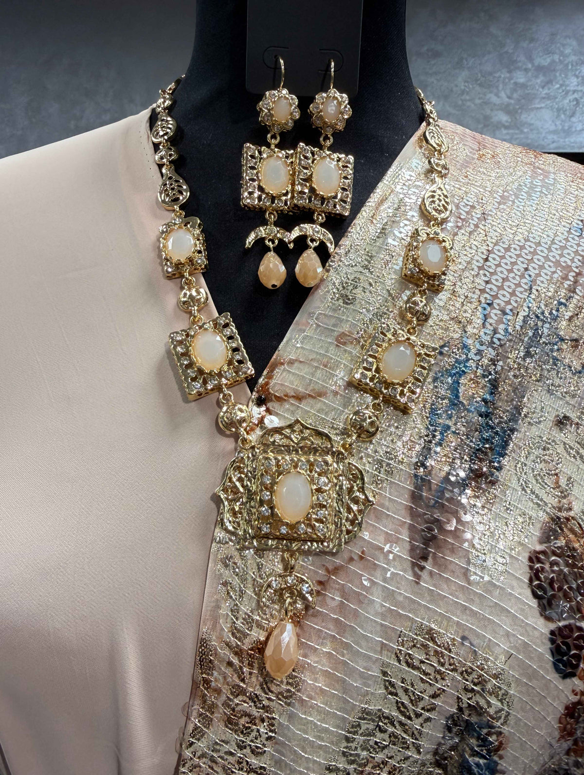 Gouden Marokkaanse sieradenset met poederroze stenen, fonkelende details, een grote hanger en bijpassende oorbellen.