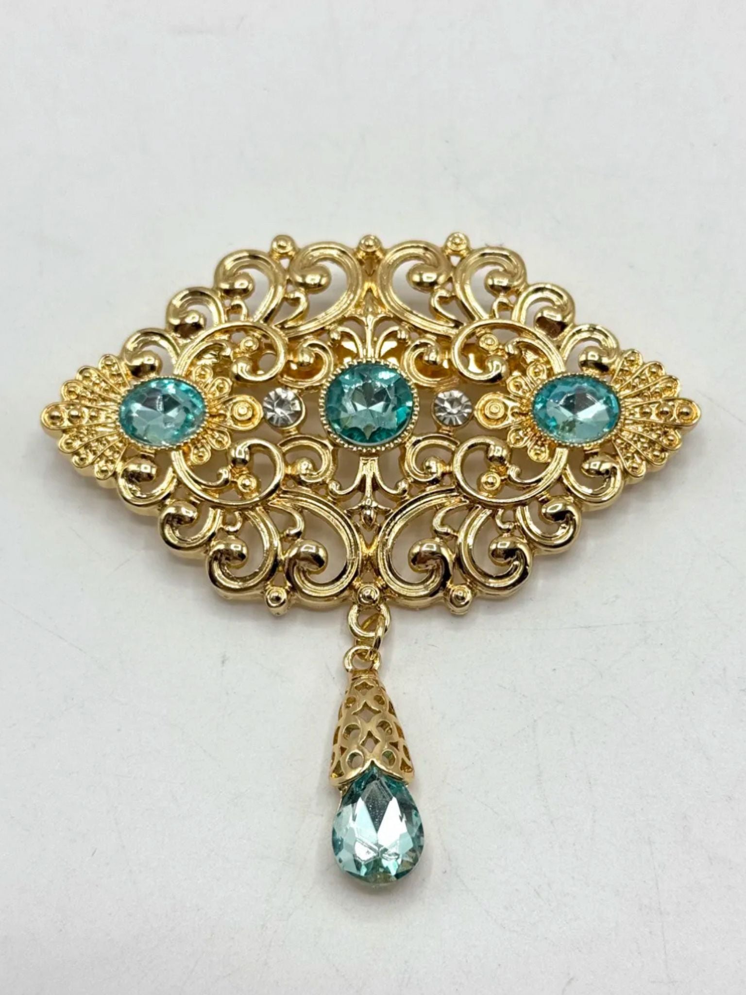 Elegante gouden broche met lichtblauwe stenen, perfect als accessoire bij takshita of feestelijke kleding.
