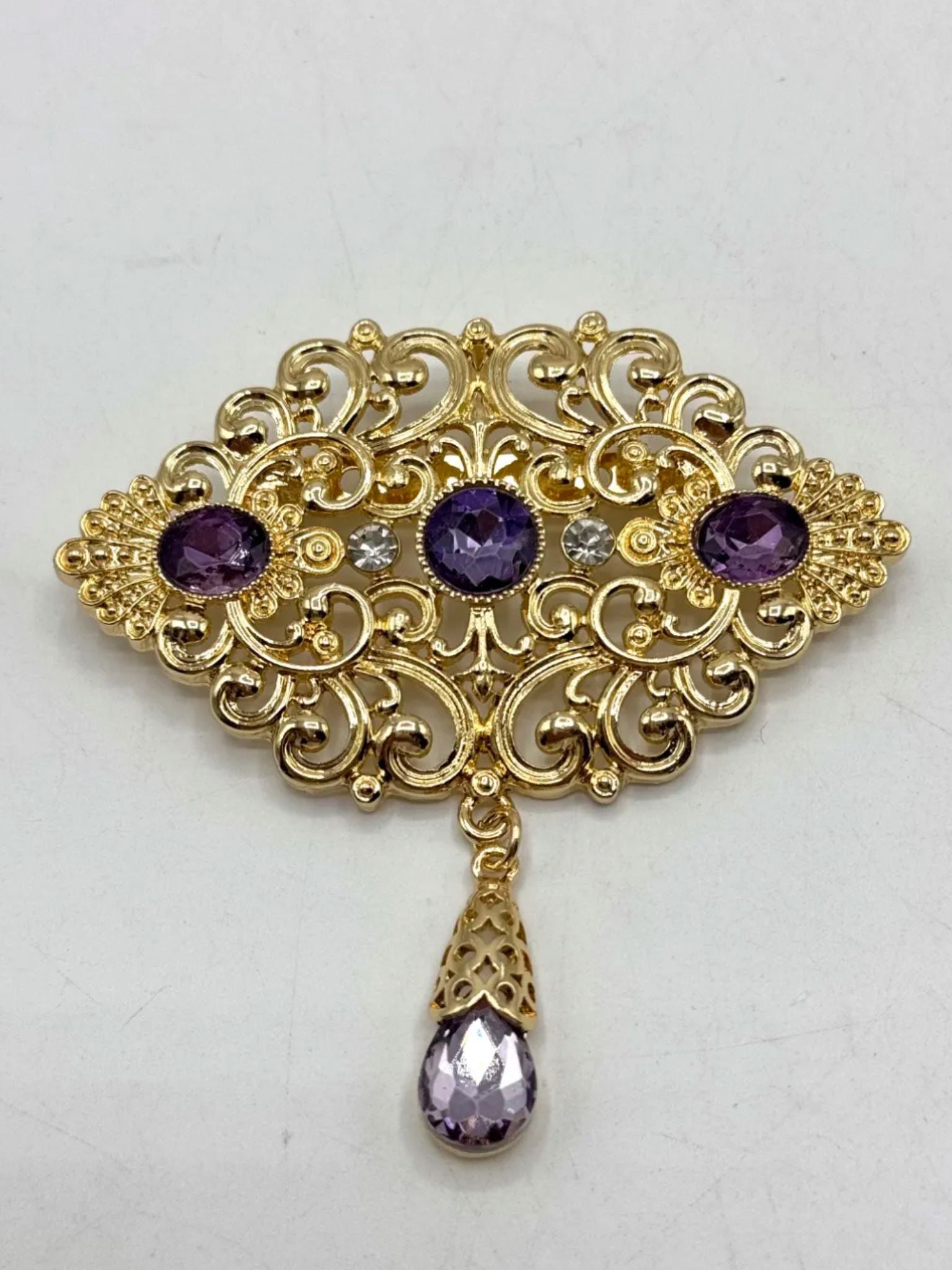 Elegante gouden broche met paarse stenen, perfect als accessoire bij takshita of feestelijke kleding.