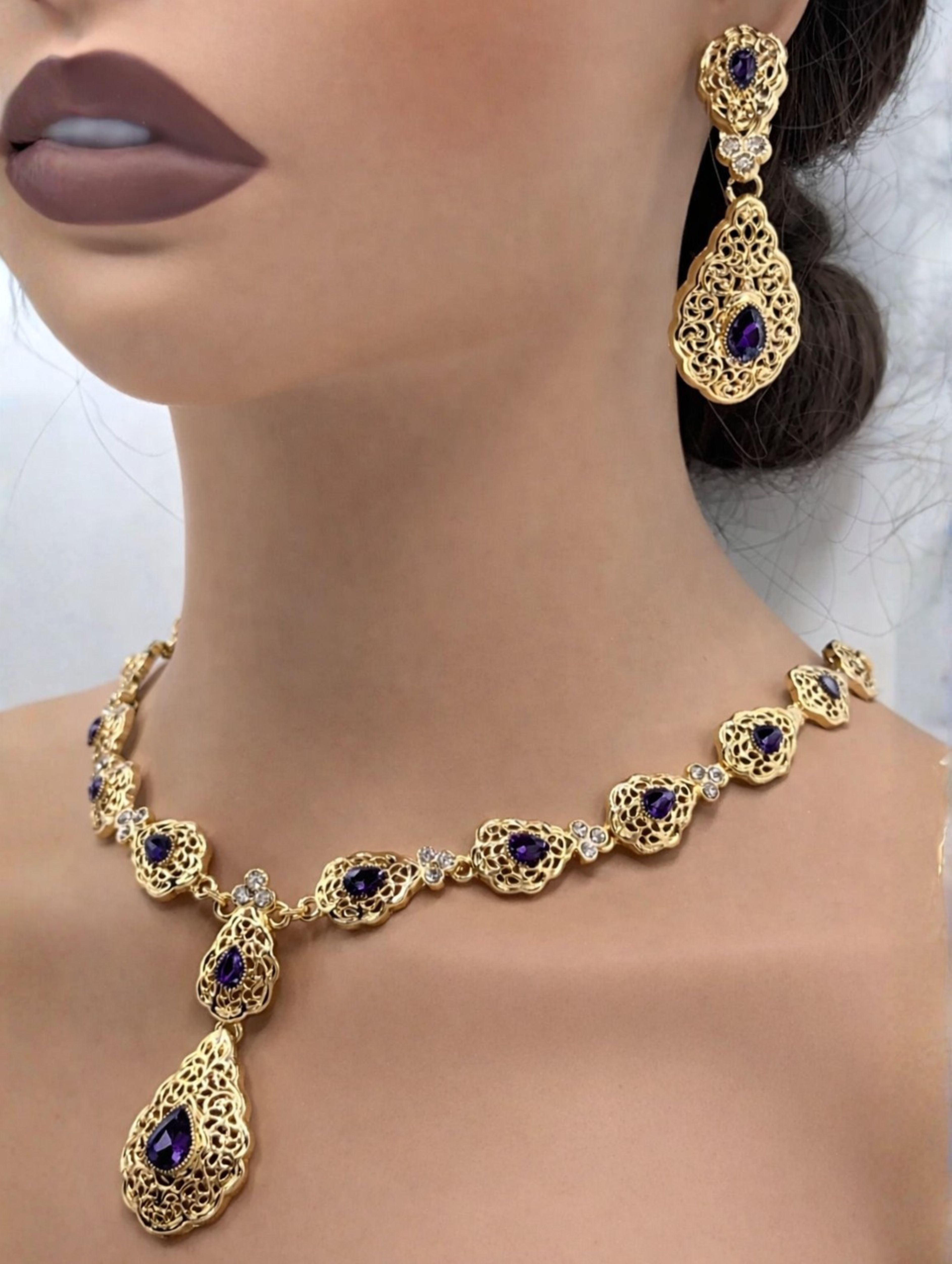 Elegante gouden ketting met oorbellen met donker paarse stenen, ideaal bij een takshita of feestelijke outfit.