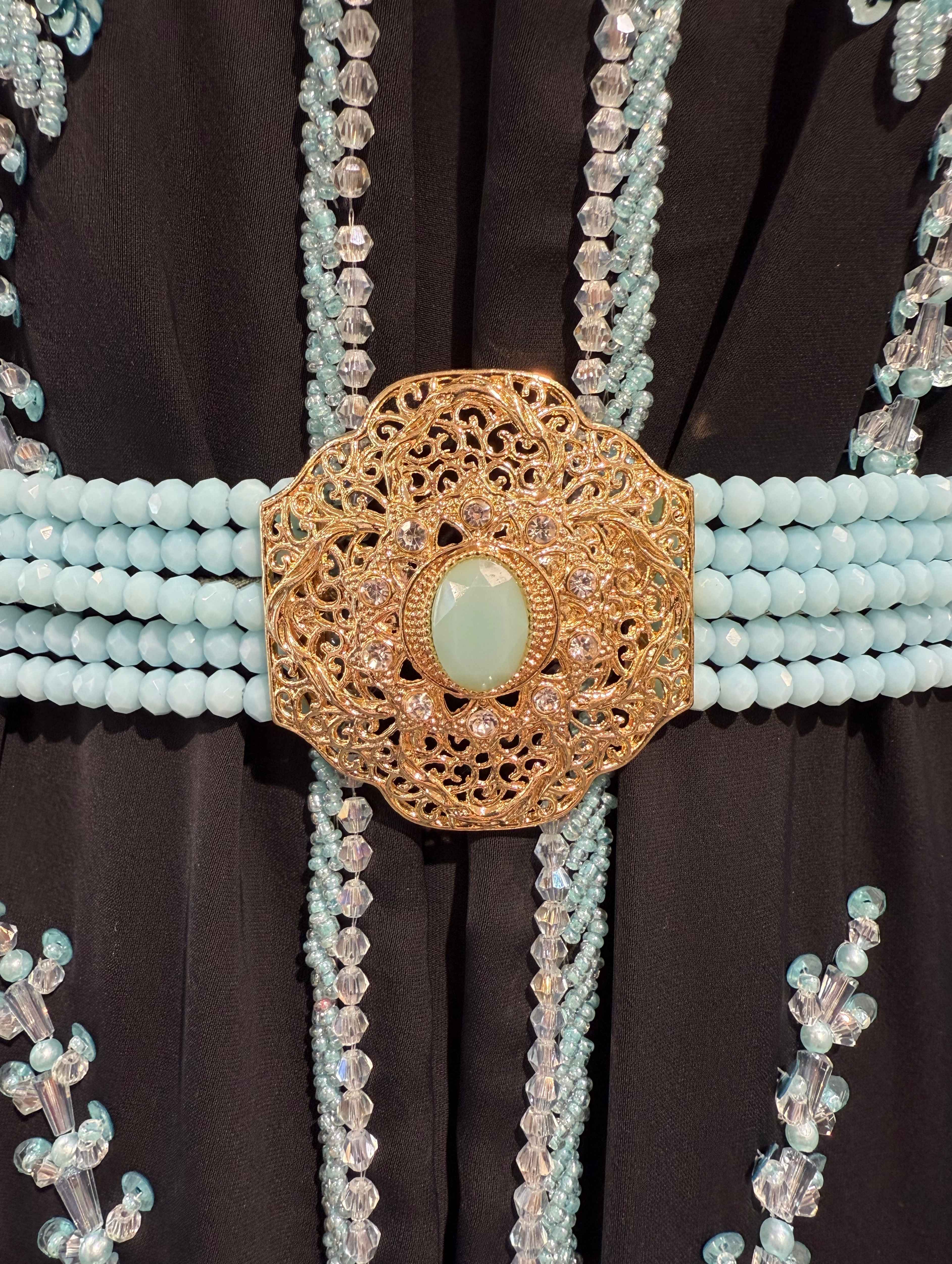 Close-up van lichtblauwe stenen en kralen op gouden riem