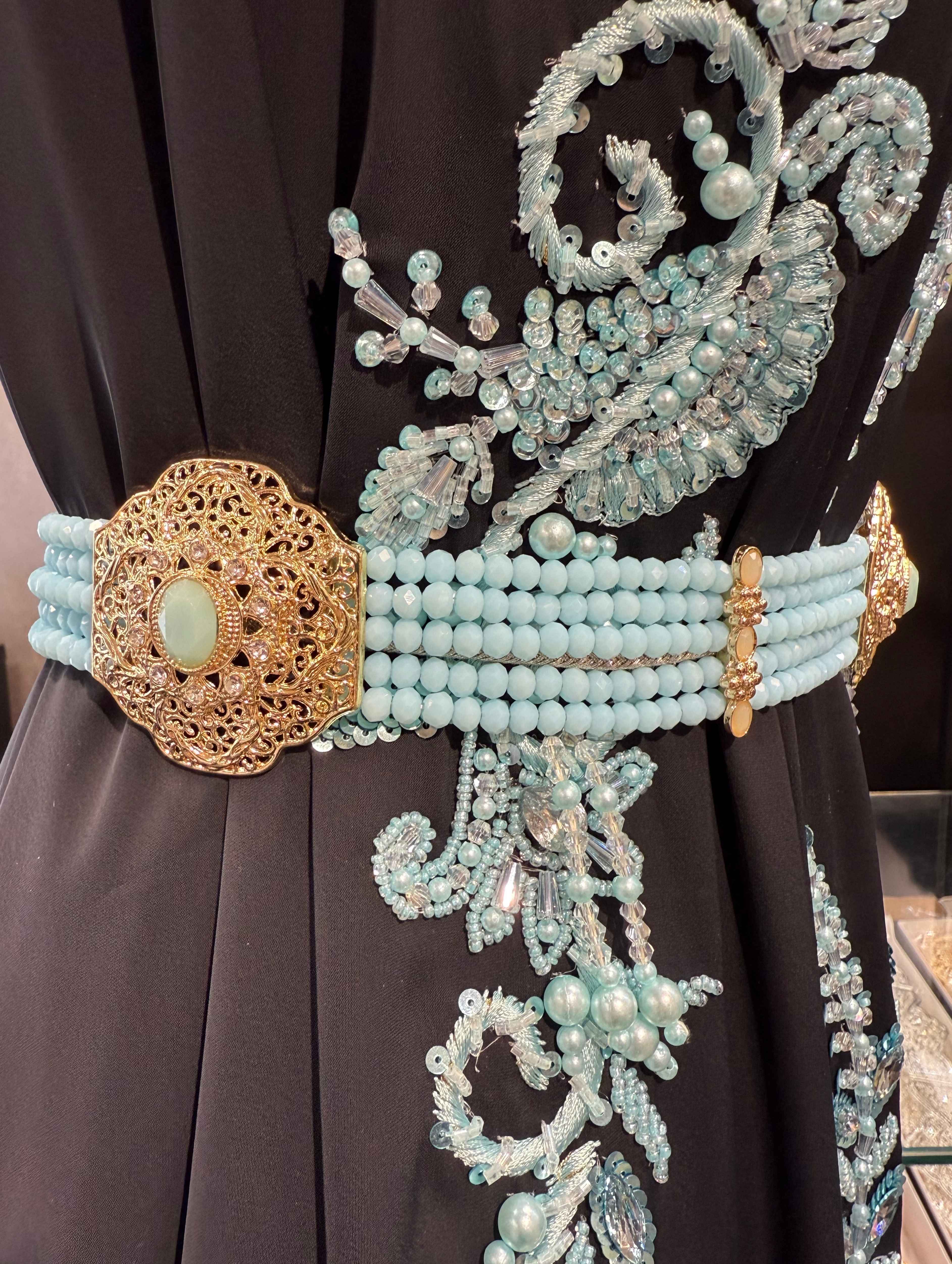 Zijaanzicht van gouden riem met lichtblauwe stenen en kralen