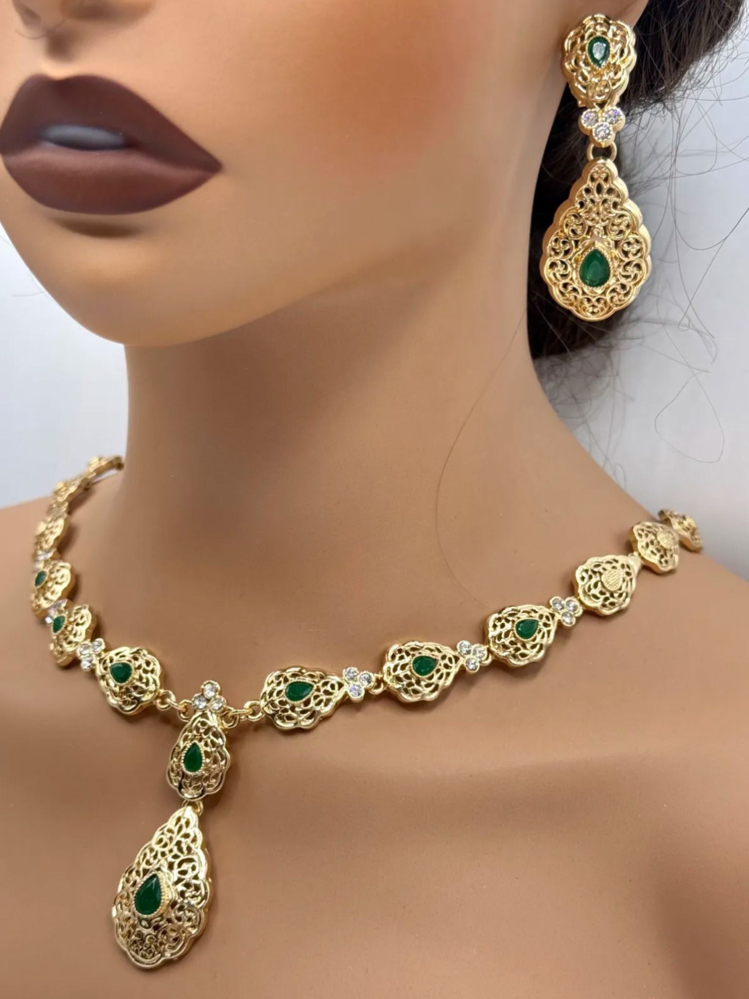 Elegante gouden ketting met bijpassende oorbellen, versierd met fonkelende groene stenen voor een luxe uitstraling