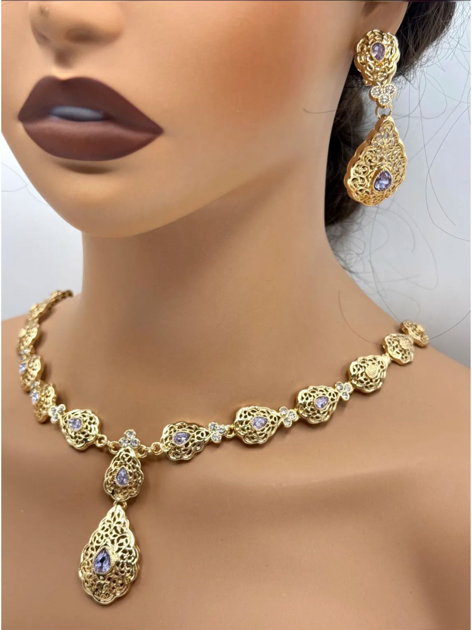 Elegante gouden ketting met bijpassende oorbellen, versierd met fonkelende lila stenen voor een luxe uitstraling