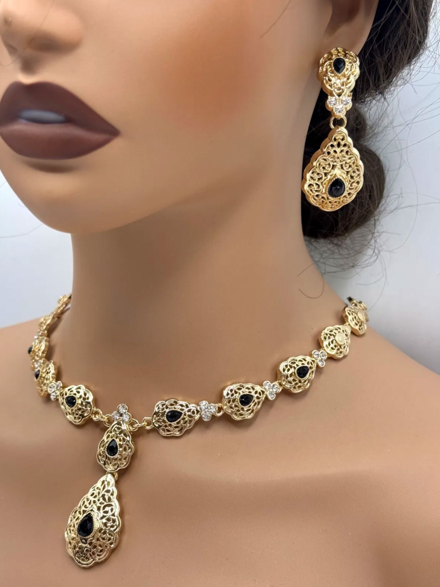 Elegante gouden ketting met bijpassende oorbellen, versierd met zwarte stenen.