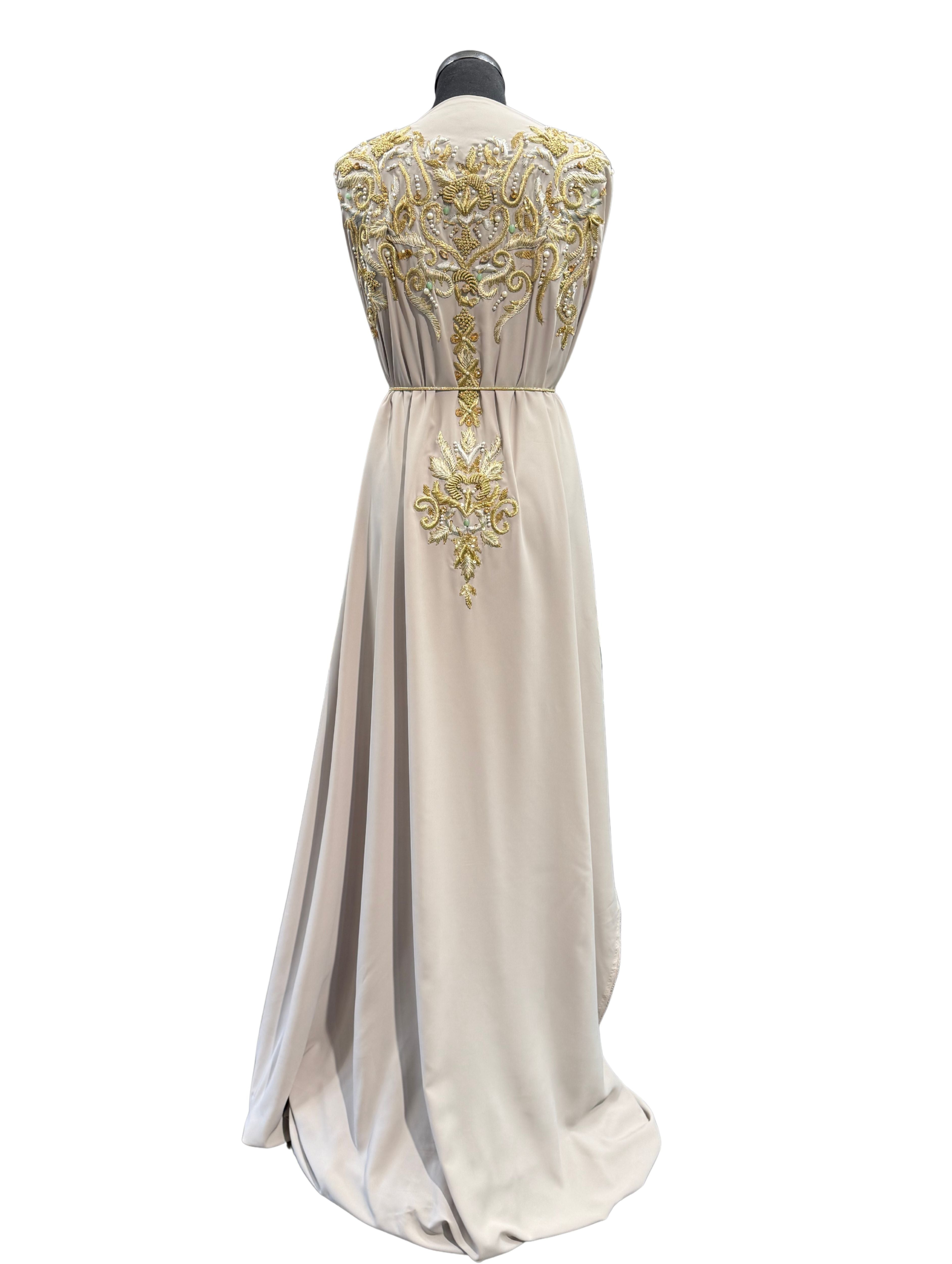 Achterkant van grijsbeige soepel vallende crêpe stof met goudkleurig borduurwerk en mintgroene kralen.