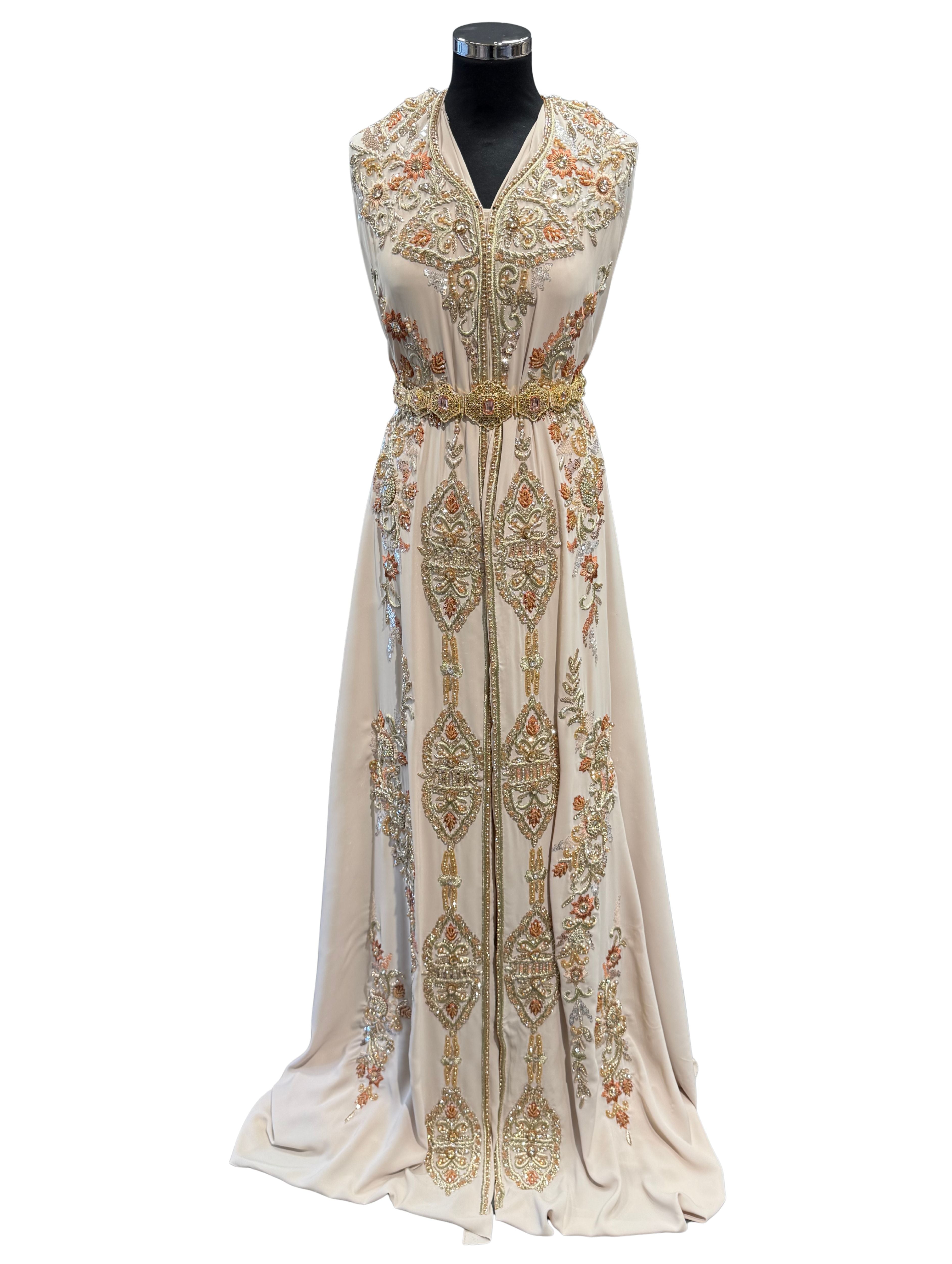 Voorkant van beige takshita stof met geborduurde bloemen en gouden stenen, geschikt voor luxe en feestelijke kleding.