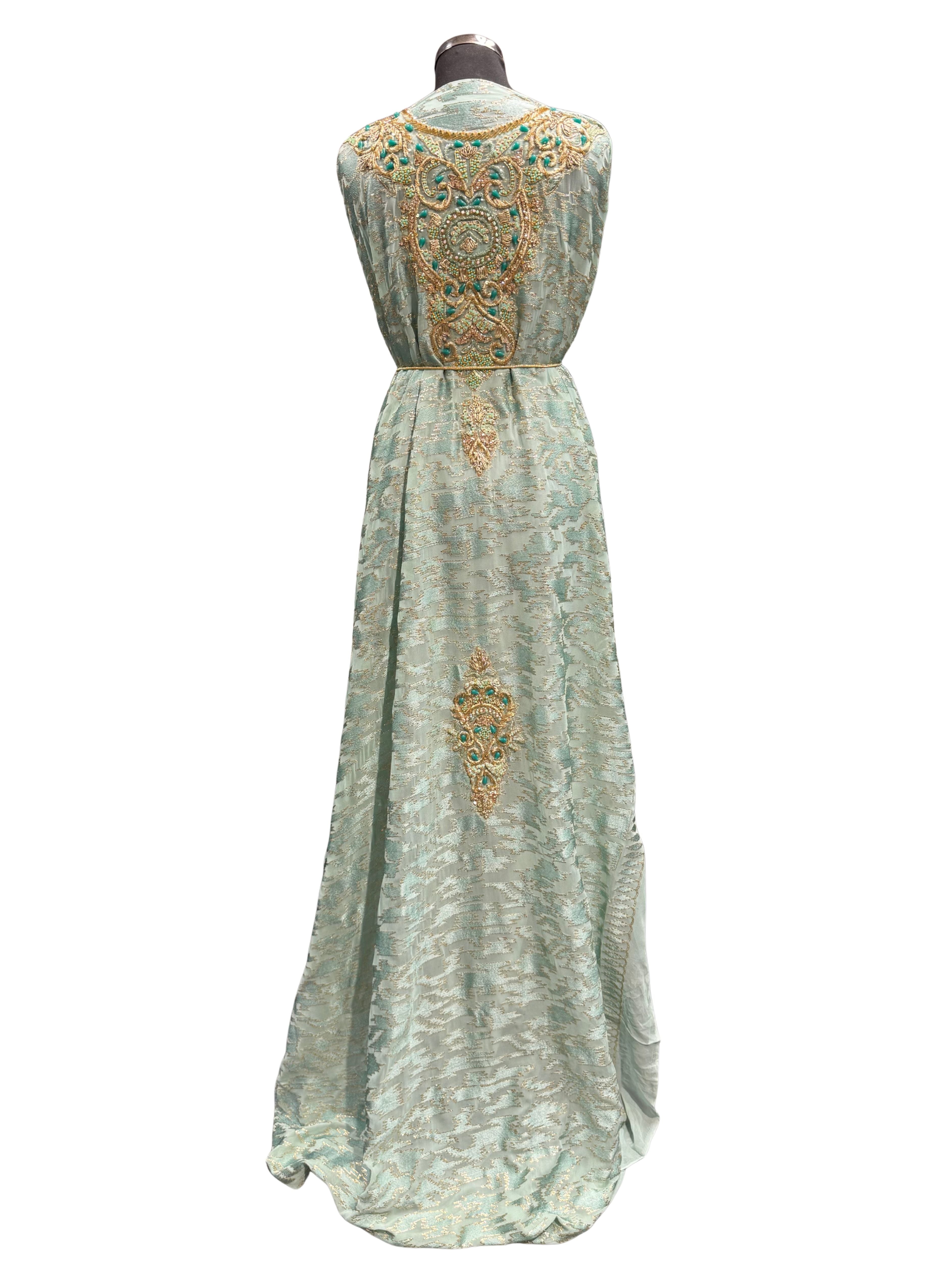 Achterkant van zeegroene semi-transparante takshita stof, bewerkt met kraaltjes en stenen, met zeegroene crepe onderstof.