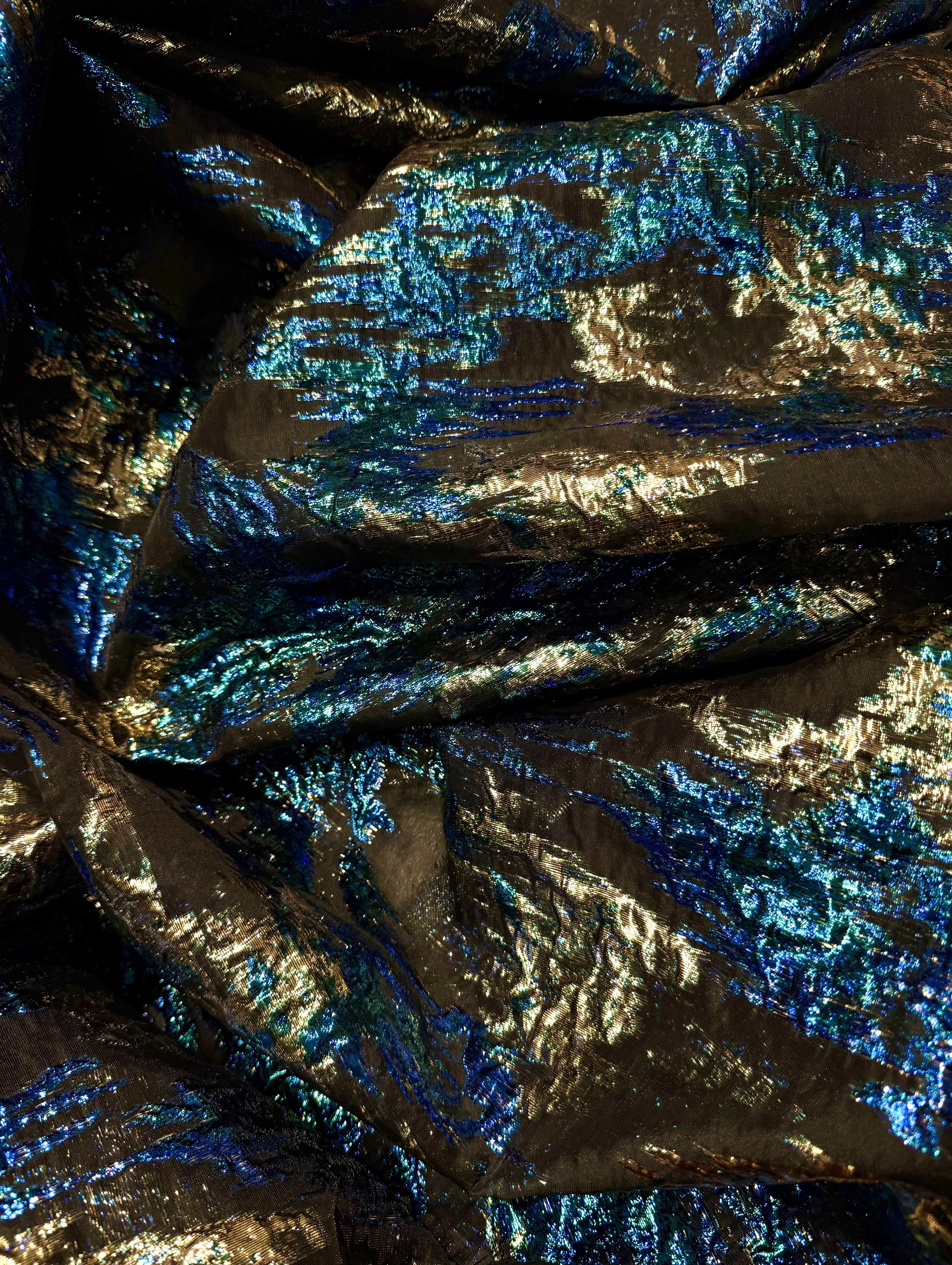 Luxe zwarte brokaat stof met blauwe en gouden glansdetails op een transparante basis.