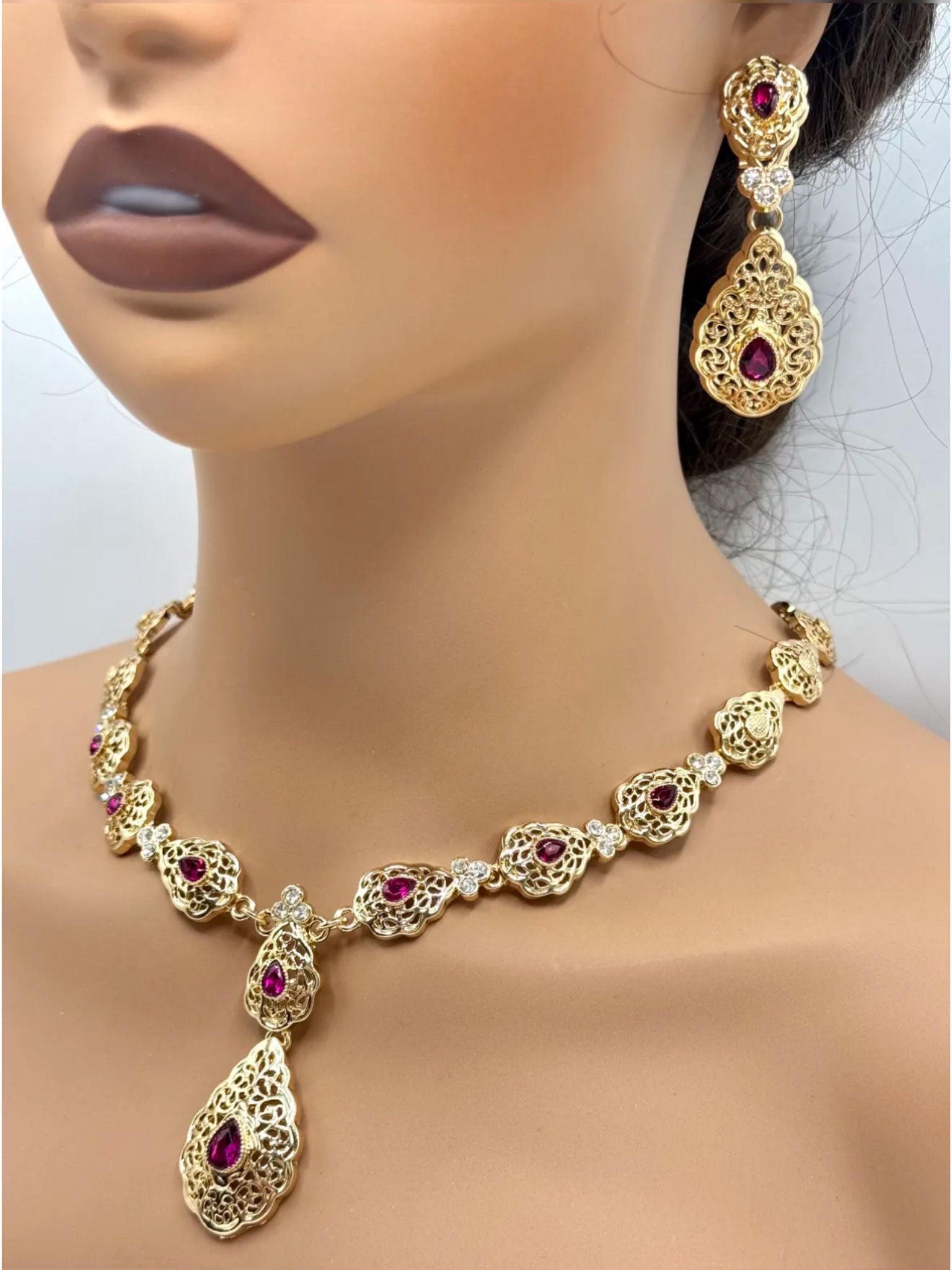 Elegante gouden ketting met bijpassende oorbellen, versierd met fonkelende fuschia stenen voor een luxe uitstraling