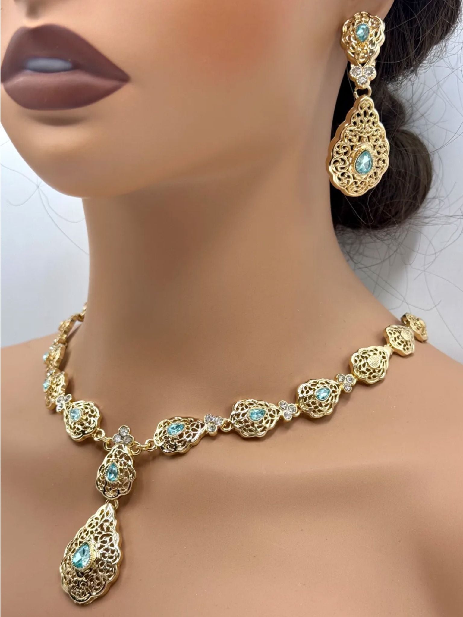 Elegante gouden ketting met bijpassende oorbellen, versierd met fonkelende licht blauwe stenen voor een luxe uitstraling