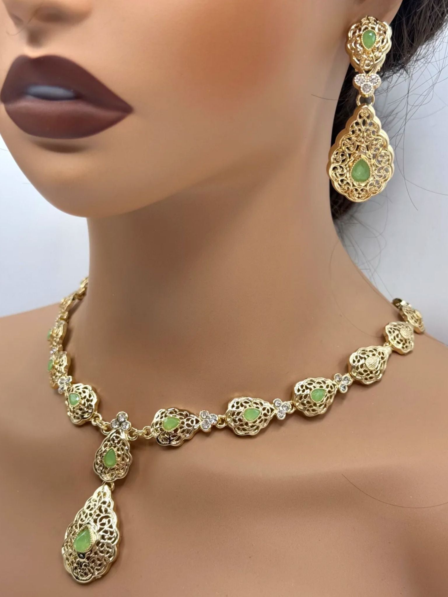 Elegante gouden ketting met bijpassende oorbellen, versierd met fonkelende mint groene stenen voor een luxe uitstraling
