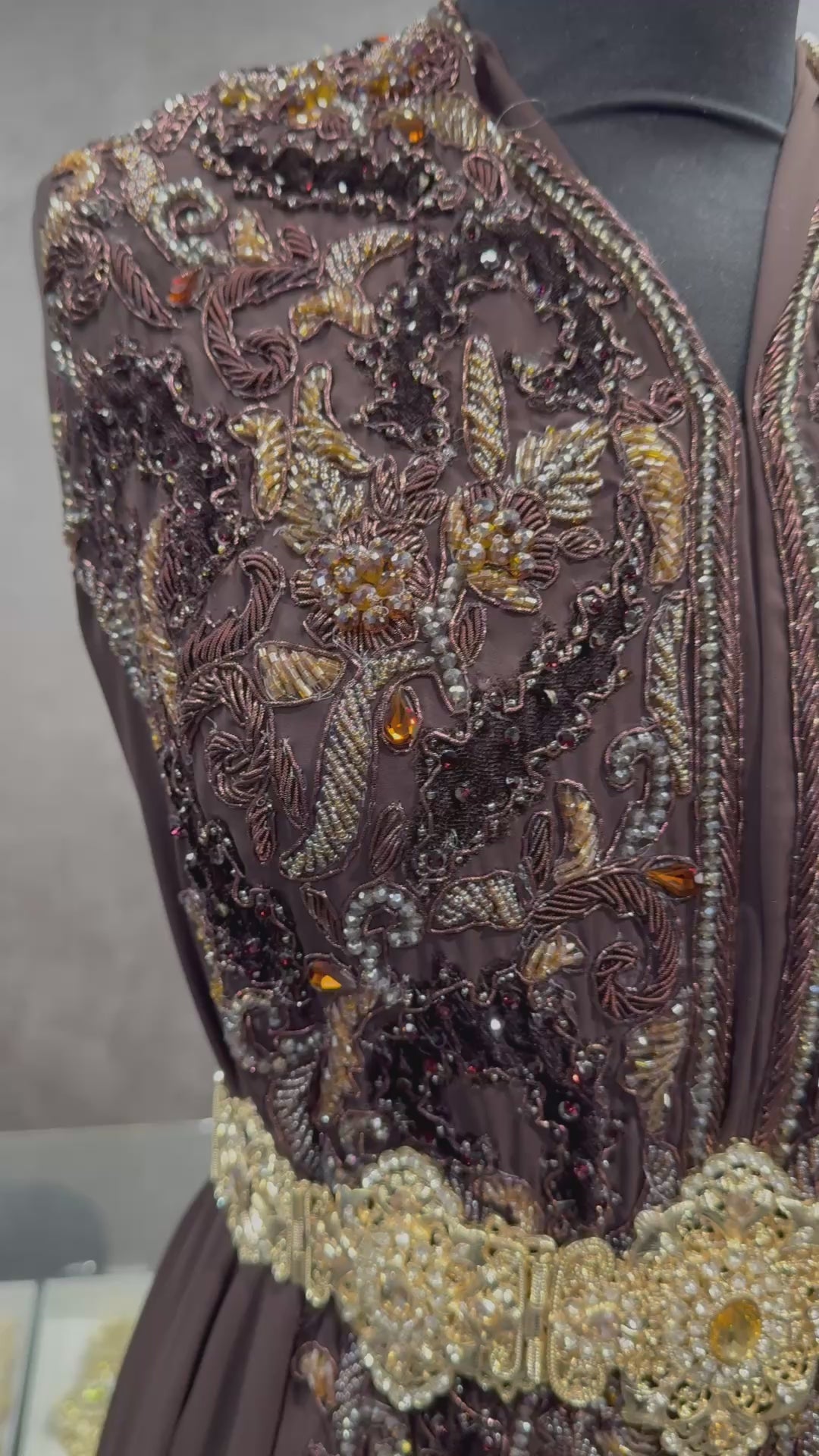 Video van donkerbruine soepel vallende crêpe stof, afgewerkt met tone-sur-tone details van kralen, stenen en velours patches.