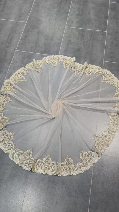 Video van ronde bruidssluier van tule in beige met gouden borduursel, parels, kralen en steentjes.