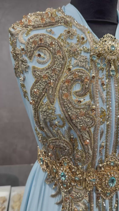 Video van lichtblauwe soepel vallende crêpe stof, afgewerkt met kraaltjes en goudkleurig borduurwerk.