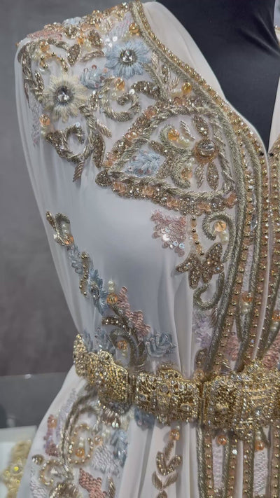 Video van crème crêpe stof voor takshita waarin de parels, pailletten, stenen, het lichtblauwe borduurwerk en de valling zichtbaar zijn.