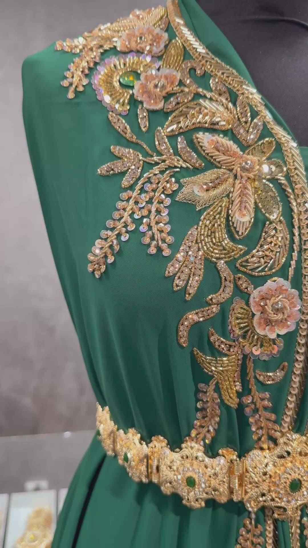 Video van donkergroene soepel vallende crêpe stof, afgewerkt met gouden versieringen.