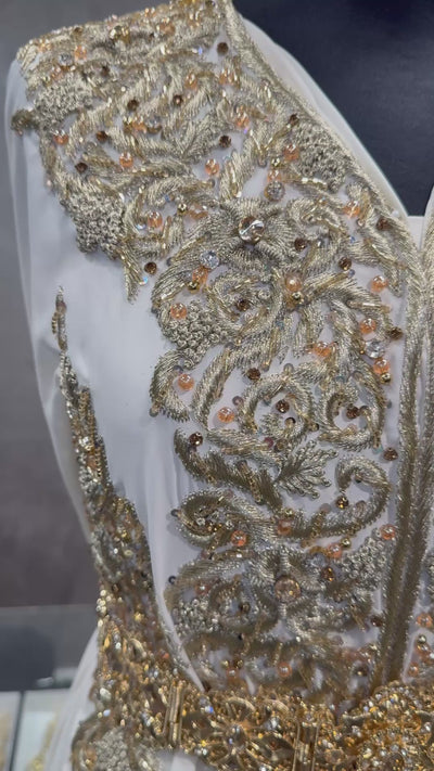 Video van crème soepel vallende crêpe stof met goudkleurig borduurwerk.