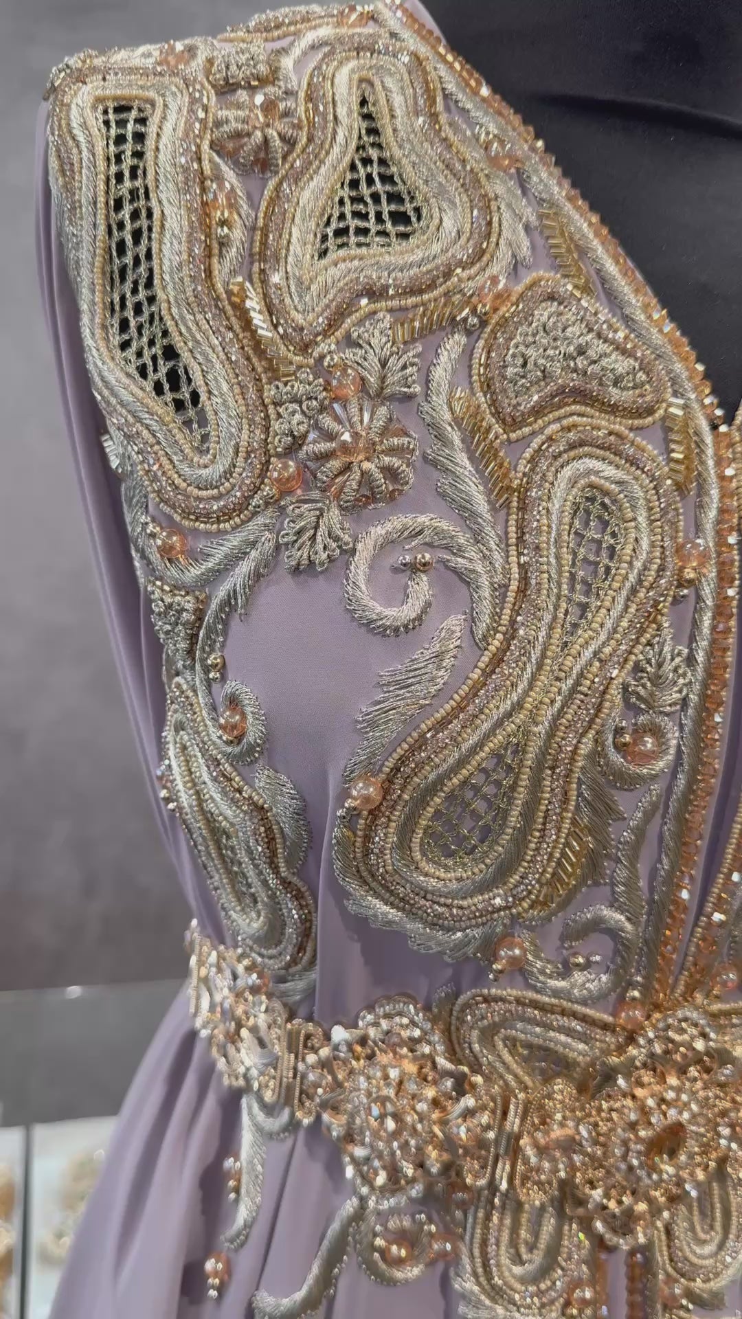 Achterkant van taupe soepel vallende crêpe stof met gouden borduurwerk, guipure, kralen en steentjes.