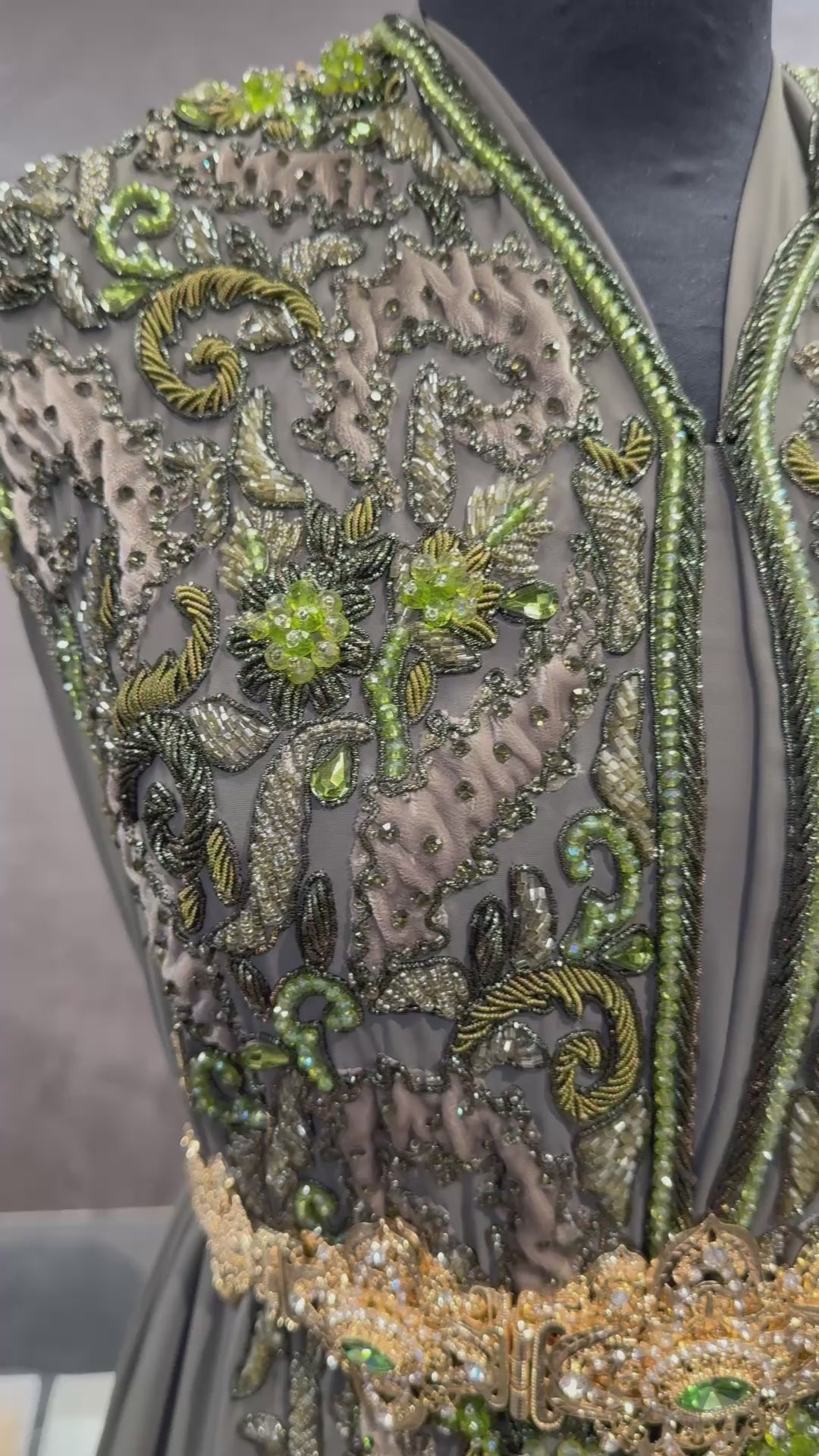 Video van mosgroene soepel vallende crêpe stof, afgewerkt met tone-sur-tone details van kralen, stenen en velours patches.